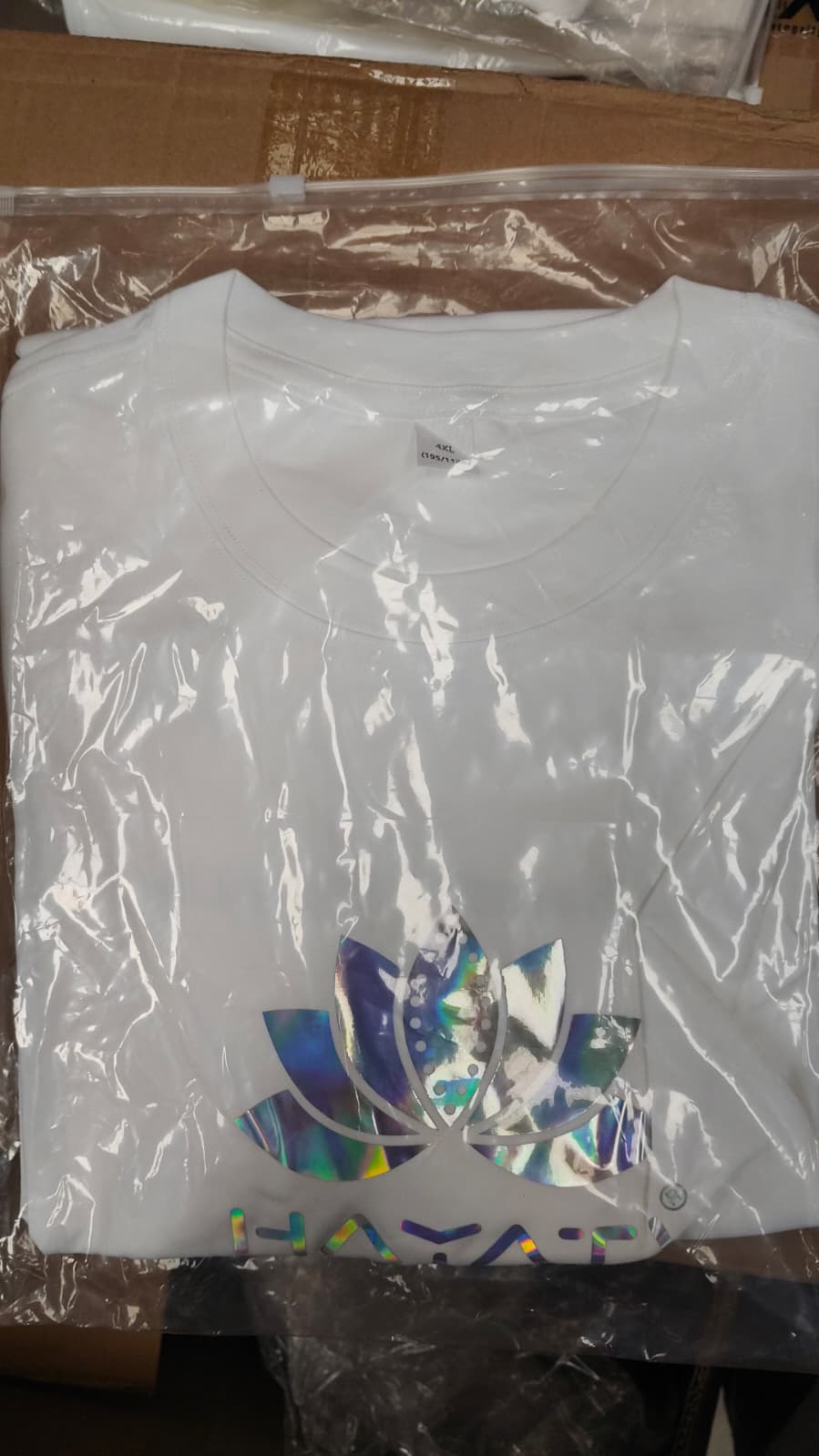 White t-shirt with colorful logo on a clear plastic bag

